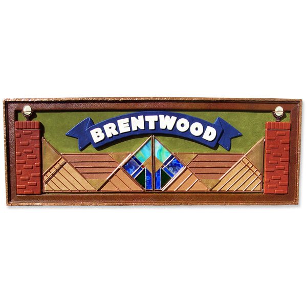 framed leather wall art hanging with name Brentwood on blue banner over stained glass and copper gate
