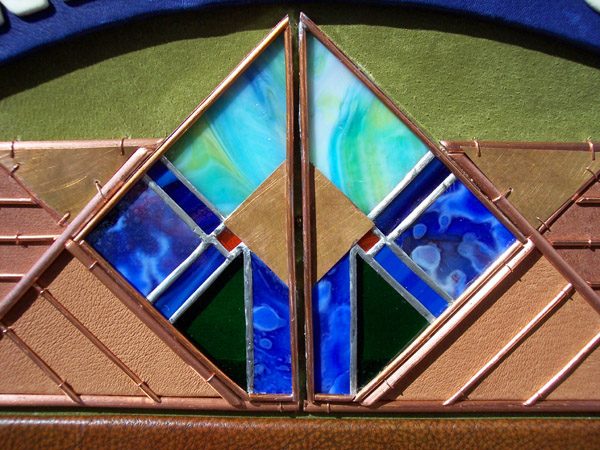 Stained glass detail on leather wall hanging with copper representing a property gate