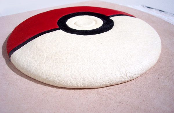 closeup of red, white, and black leather Pokeball on pink leather book cover