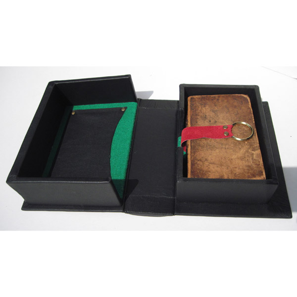 black leather clamshell box containing an antique book with red suede lift cord