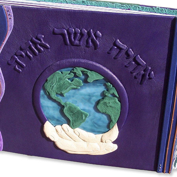 hands holding earth design in stained glass and leather on custom leather photo album cover with Hebrew words