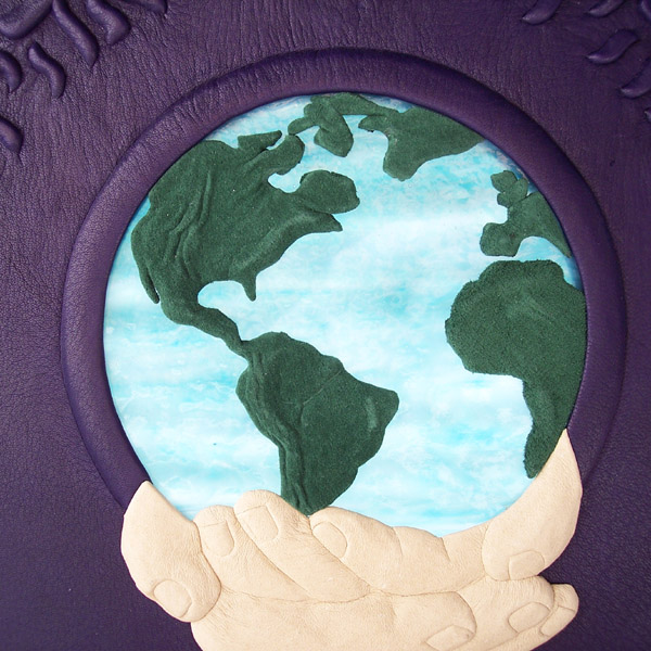 hands holding globe with backlit stained glass earth and leather continents on purple leather book cover