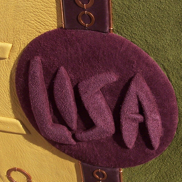 Name LISA handcarved and embossed under burgundy leather on round panel on book cover