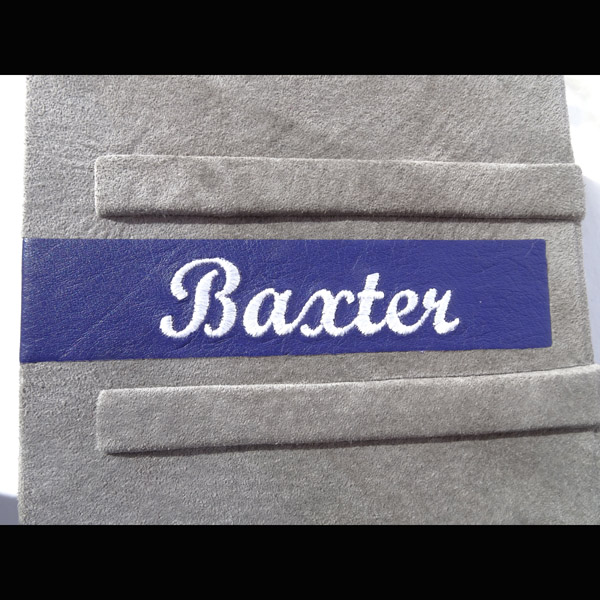 Baxter embroidered on back of leather book cover in white thread on purple leather